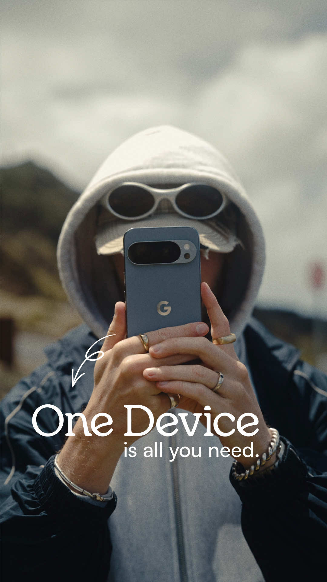 Ohneis652 holding a smartphone and gesturing toward the screen, with a frame-within-frame composition suggesting a camera lens in the foreground